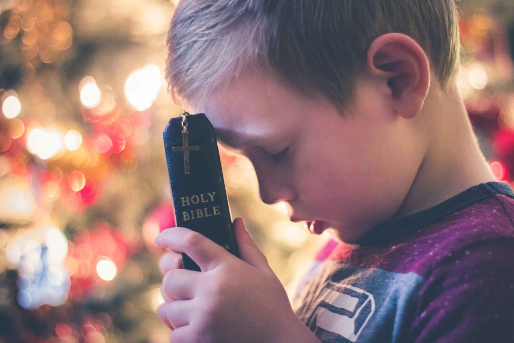 Kid praying and Holding the bible